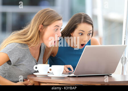 Zwei erstaunt Friends skandalösen Inhalt in einem Laptop sitzen in einer Bar Stockfoto