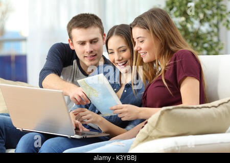 Drei glückliche Freunde die Planung einer Reise auf Leitung und Beratung ein Wegweiser auf einem Sofa zu Hause sitzen Stockfoto
