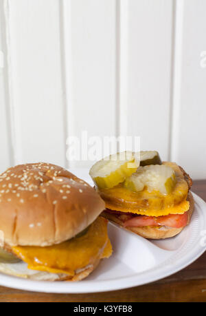 Zwei vegetarische Cheeseburger mit Gurken und Tomaten auf einer Platte Stockfoto