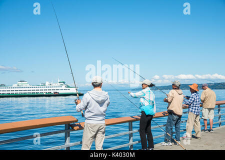 Männer und Frauen Angeln aus Pier mit der Fähre im Hintergrund, Edmonds, Washington Stockfoto