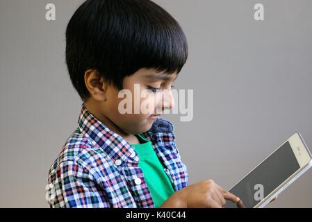 Kid mit Technologie Schuß in natürlichem Licht. Kid mit Kopfhörern auf Tablet-PC suchen. Kind mit Kopfhörern über Tablet. Stockfoto