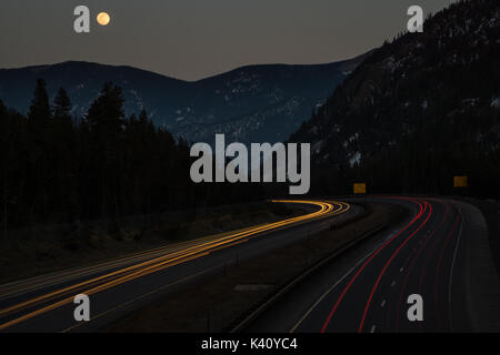 Eine lange Belichtung geschossen von der I-70 mit einem Vollmond über den Bergen. Stockfoto