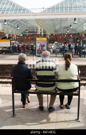 Drei Leute sitzen, warten auf eine U-Bahn station Tynemouth, North East England, Großbritannien Stockfoto