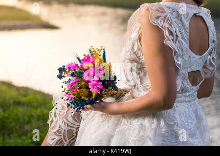 Braut Hochzeit halten, bunten Blumenstrauß am See Stockfoto