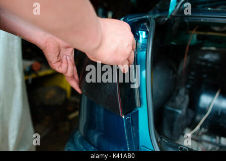 Closeup Instandsetzung eines defekten blaues Auto in der Garage durch die Hände von machanic. Stockfoto