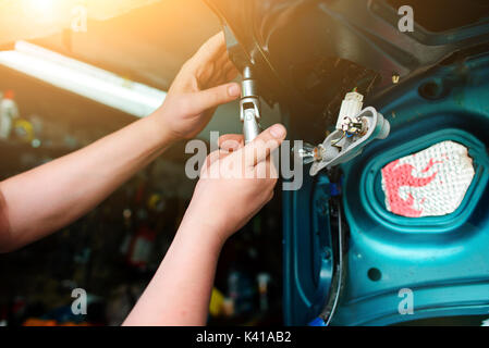Closeup Instandsetzung eines defekten blaues Auto in der Garage durch die Hände von machanic. Stockfoto
