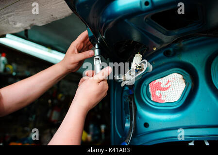 Closeup Instandsetzung eines defekten blaues Auto in der Garage durch die Hände von machanic. Stockfoto