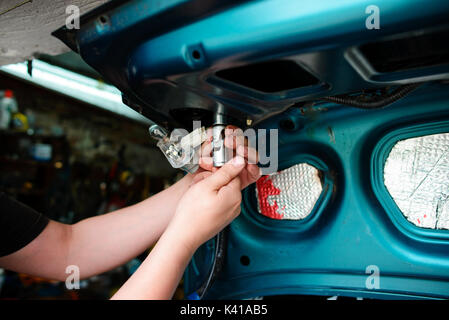Closeup Instandsetzung eines defekten blaues Auto in der Garage durch die Hände von machanic. Stockfoto