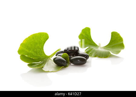 Ginkgo Blätter mit Gel Kapseln auf weißem Hintergrund mit Reflexion isoliert. Alternative Medizin, Nahrungsergänzung, natürliche Heilmittel. Stockfoto