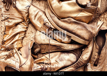 Paar alten verschlissenen Schuhe und Stiefel in goldgelber Farbe lackiert Stockfoto