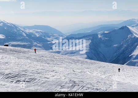 Zwei Skifahrer bergab auf Schnee abseits der Pisten und Berge im Dunst bei Sun winter Tag. Kaukasus, Georgien, Region Gudauri. Stockfoto