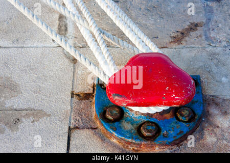 Retro Rusty Red und Blue dock Poller auf dem steinernen Pier mit Seilen für Befestigt das Schiff Stockfoto