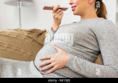 Schwangere Frau mit Voice-Recorder auf smartphone Stockfoto
