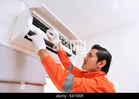 Jungen asiatischen männlichen Techniker Reparatur der Klimaanlage zu Hause Stockfoto