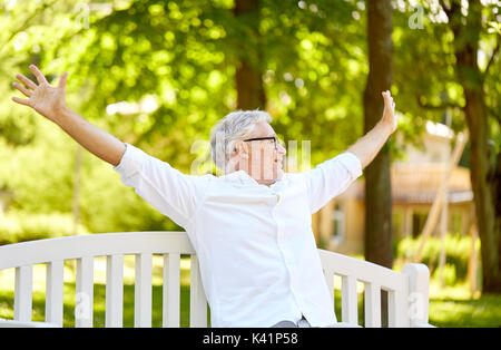Gerne älterer Mann sitzt auf der Bank im Park Stockfoto