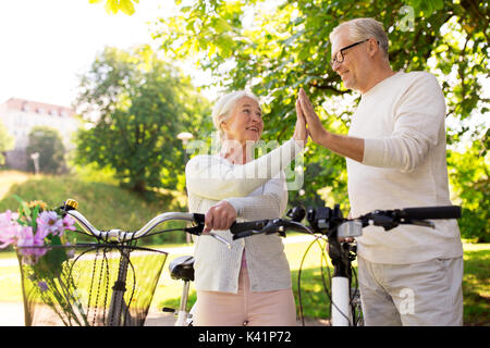 Senior Paar mit Fahrrädern hoch fünf im Park Stockfoto