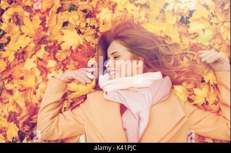 schöne glückliche Frau liegend auf Blätter im Herbst Stockfoto