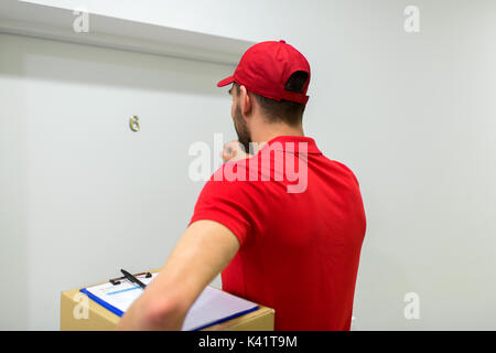 Lieferung Mann mit Paketbox Tür klopfen Stockfoto