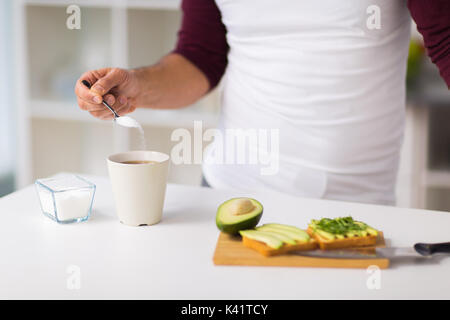 Man Frühstücken und Zugabe von Zucker zum Kaffee Stockfoto