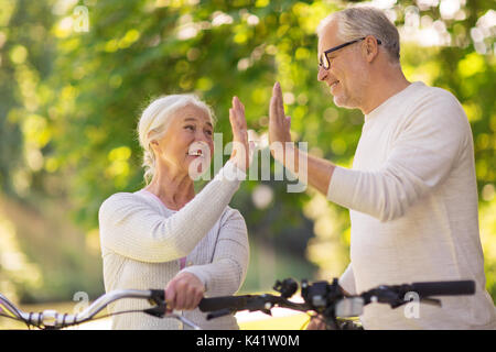 Senior Paar mit Fahrrädern hoch fünf im Park Stockfoto