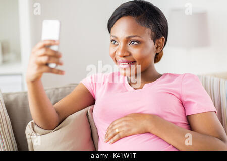 Schwangere Frau unter Smartphone Selfie zu Hause Stockfoto