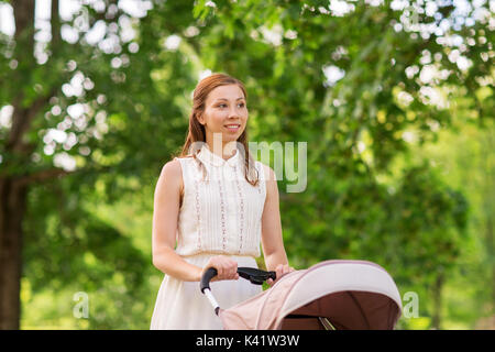 Glückliche Mutter mit Kind im Kinderwagen im Summer Park Stockfoto