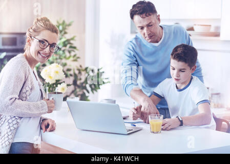 Strahlend lächelnde Frau mit Mann und Kind im Hintergrund arbeiten Stockfoto