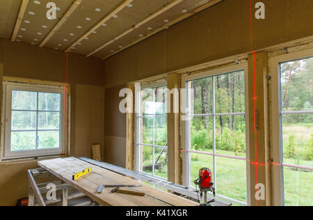 Bauarbeiten, Abschluss der Arbeiten in einem Holzhaus und Windows Installation mit der Ebene der Laserlinie Stockfoto