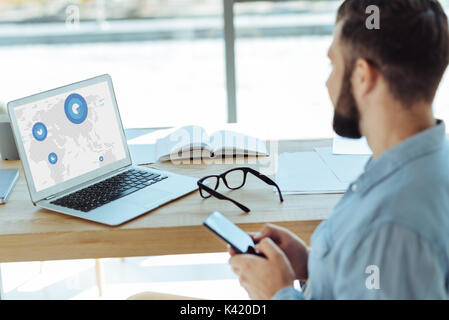 Junger Mann an die Charts auf dem Laptop Bildschirm schaut Bärtigen Stockfoto