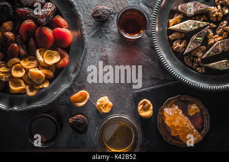 Getrocknete Früchte, Nüsse auf einer Platte und einem Kaffee auf grauem Schiefer close-up horizontal Stockfoto