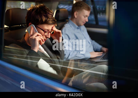 Die Nacht - müde Business woman Verwendung des Smartphones im Auto Stockfoto