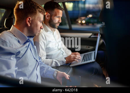 Müde Geschäftsleute arbeiten am späten Abend in Rücksitz des Autos Stockfoto