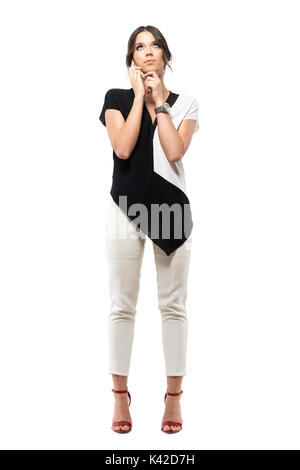 Nachdenkliche junge geschäftsfrau auf dem Handy reden und oben zu schauen. Voller Körper Länge Porträt auf weißem studio Hintergrund isoliert Stockfoto