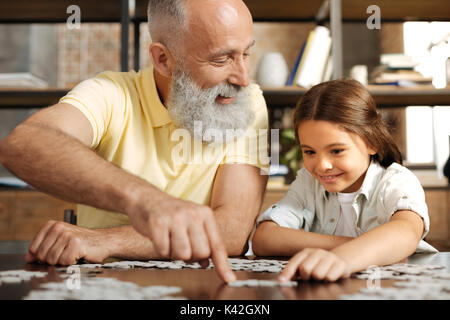 Adorable kleine Mädchen Montage Puzzle mit ihrem Großvater Stockfoto