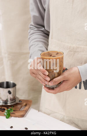 Zugeschnittenes Bild von Stattlichen barista in Schürze halten einer Tasse Kaffee Stockfoto
