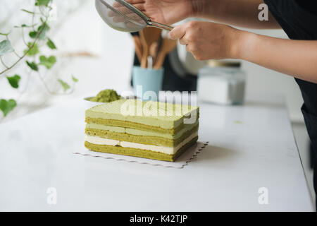 Gießen grüner Tee Pulver über leckeren Käsekuchen Stockfoto