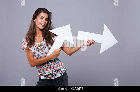 Fröhliches Mädchen mit vertikalen und horizontalen Pfeil Zeichen Stockfoto
