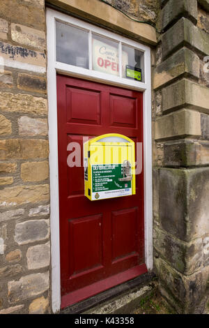 Öffentlichen Defibrillators in einem gelben Feld zu einer Tür im Stadtzentrum von Richmond, North Yorkshire Dales, England, Großbritannien Stockfoto