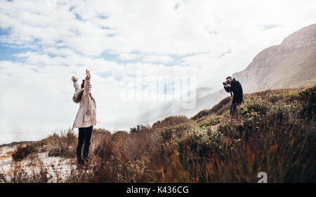 Mann seine Freundin fotografieren mit der digitalen Kamera im Freien. Junges Paar im Urlaub Fotos machen. Stockfoto