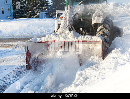 Schneefräse an einem Traktor angebauten Reinigung aus einem Wohngebiet Auffahrt. Stockfoto