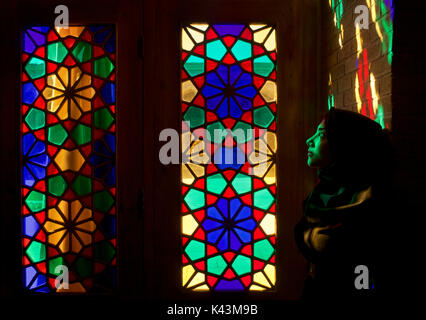 Sonnenlicht beleuchtet die Glasmalerei der Winter Gebetsraum der Nazir ul-Mulk Moschee Shiraz, Iran. Portrait von muslimischen Frau Stockfoto