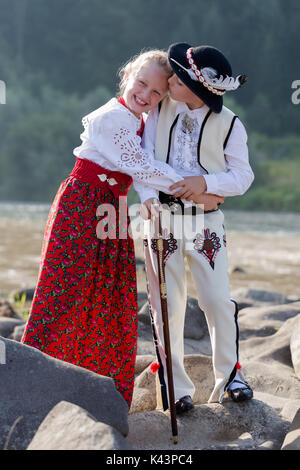Geschwister, Bruder spontan Küssen lächelnde Schwester. Kinder tragen traditionelle polnische Berg Menschen Kleidung steht auf Felsen am Bach. Verti Stockfoto