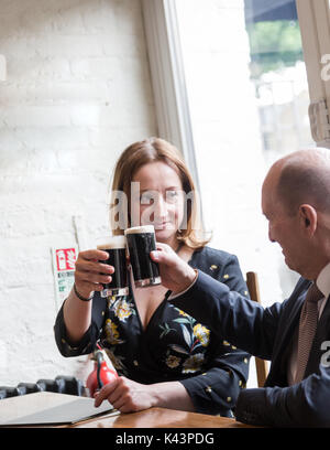 Professionelle echte Menschen, jungen erwachsenen Frau, älterer Mann, informelles Geschäftstreffen im Pub am Glas dunkles Bier. Candid unposed horizontale Schuß Stockfoto
