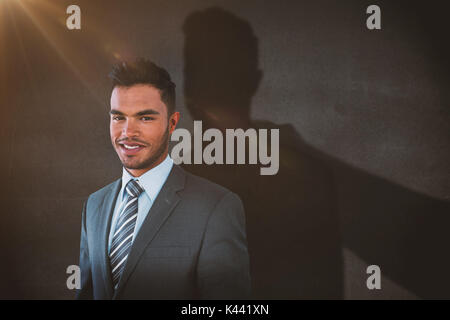 Lächelnd Geschäftsmann vor weißem Hintergrund gegen schwarze Wand Stockfoto