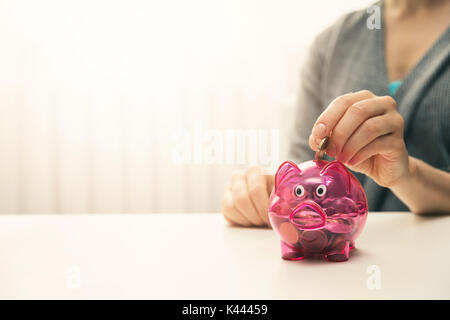 Frau die Münze in Sparschwein. Kopieren Sie Platz Stockfoto