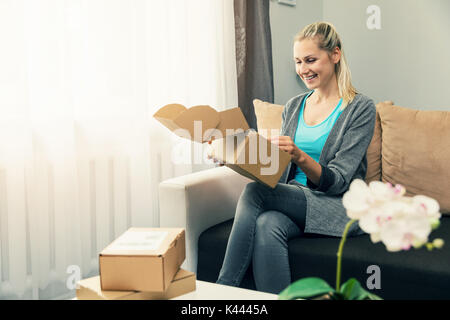 Home Delivery - lächelnden jungen Frau Eröffnung Karton Stockfoto