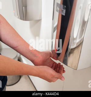 Ein Mann seine Hände trocknen mit einem warmen Lufttrockner in einer öffentlichen Toilette in Großbritannien Stockfoto