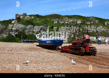 Fischer mit bulldozer Fischerboot bis zu schieben, Kiesstrand, Hastings, East Sussex, England Stockfoto