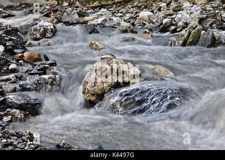 Felsbrocken in einem kleinen Gebirgsbach umgeben von sanften fließenden Wassers (Langzeitbelichtung) Stockfoto