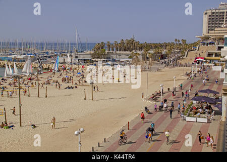 TEL AVIV - April 7th, 2015: Der Strand in Tel Aviv, mit Menschen an einem heißen Tag gepackt. Einige sind im Wasser, einige sind Radfahren oder Wandern, am 7. APRIL 20. Stockfoto